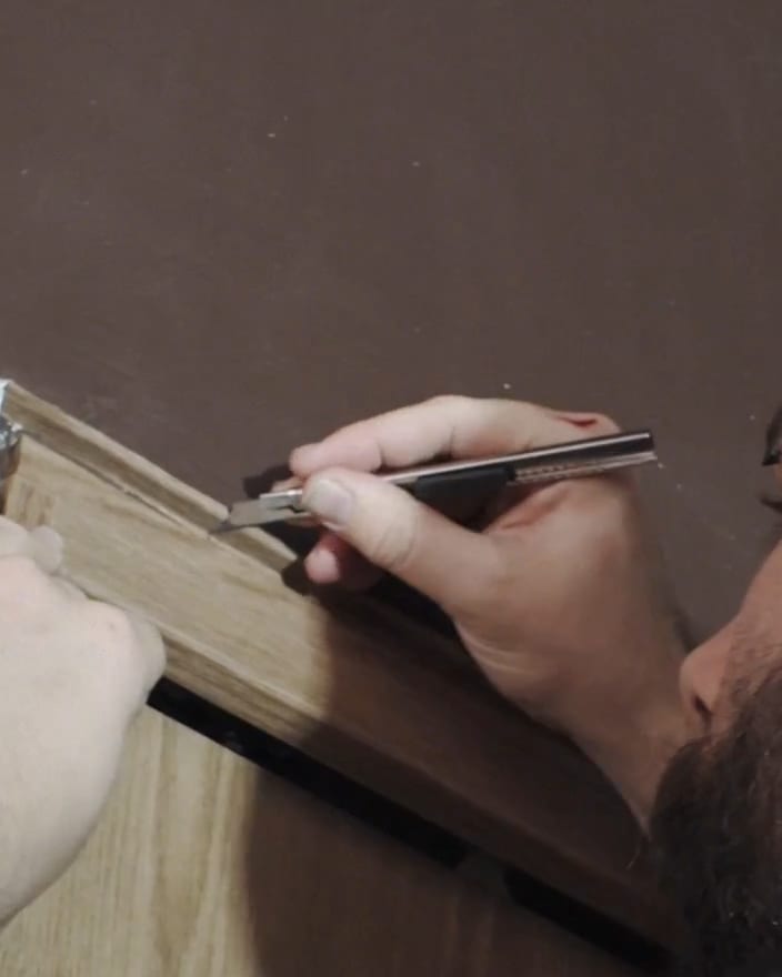 An installer trimming Maison Walnut wrap along an edge with a snap blade at The Feel Good Hood