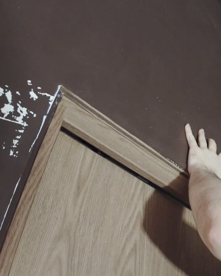An installer pressing Maison Walnut wrap into the edge of a frame at The Feel Good Hood