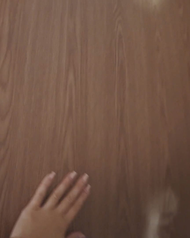 A hand resting on a finished Maison Walnut wood grain wall at The Feel Good Hood