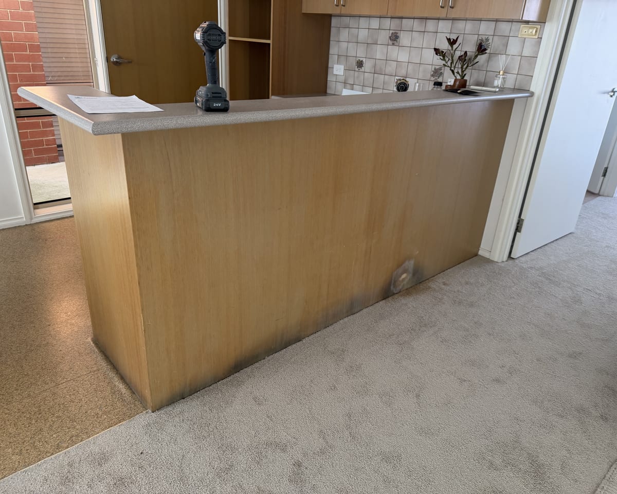 The same kitchen island before wrapping, with a pale timber finish