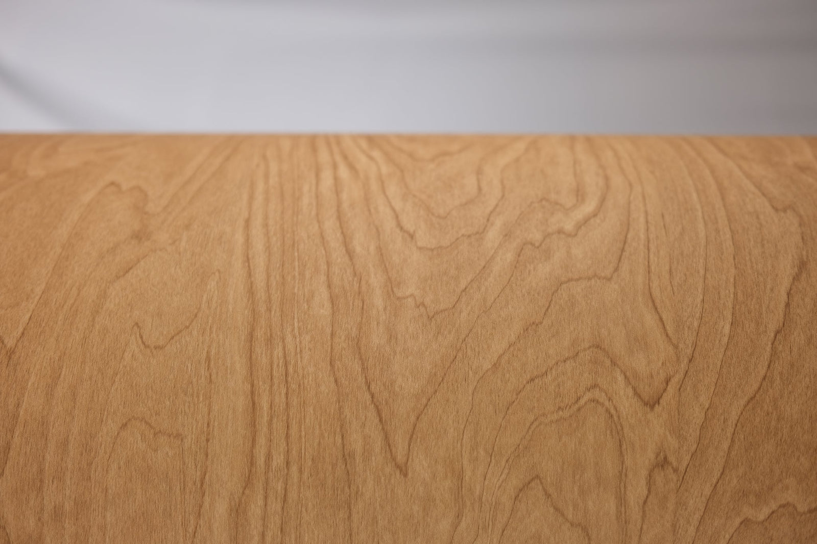 Golden cherry finish smoothed over a cabinet edge against a soft backdrop