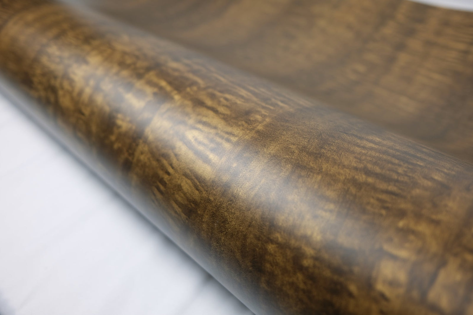 A roll of dark walnut wood grain self adhesive vinyl wrap with a soft satin sheen