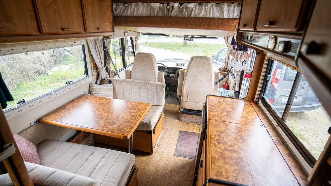 Compact campervan interior with timber cabinets, seating and a dining table