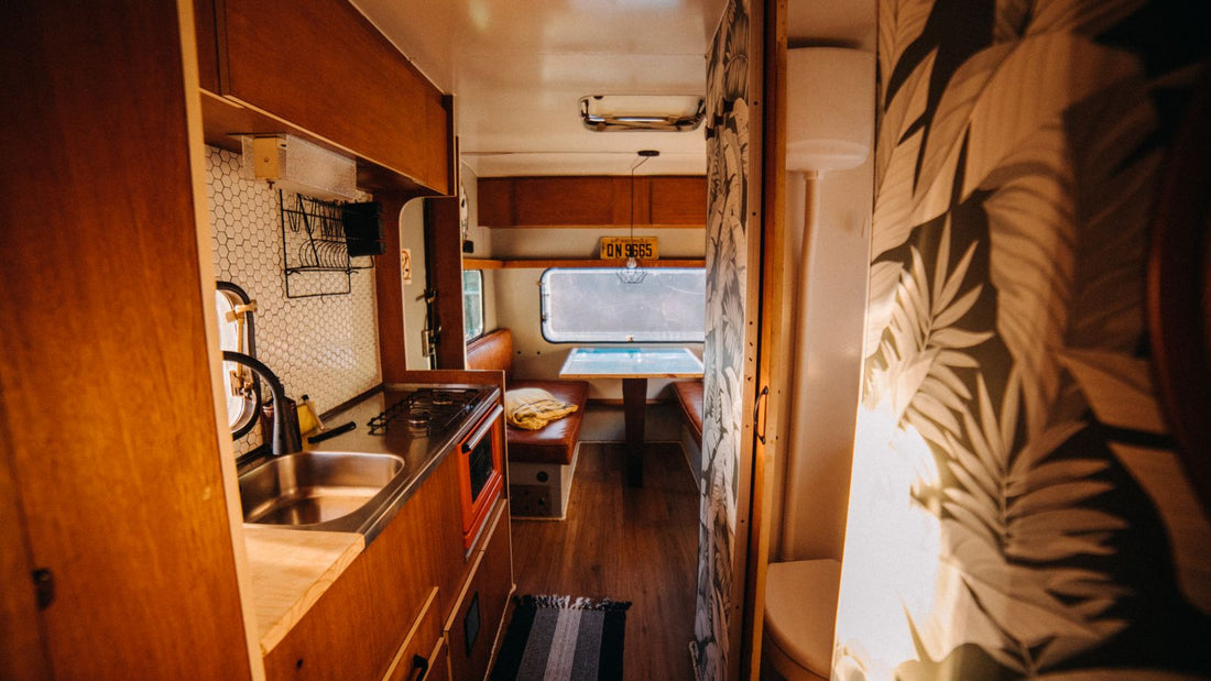 Dated timber caravan interior with wood cupboards, kitchenette and dining area
