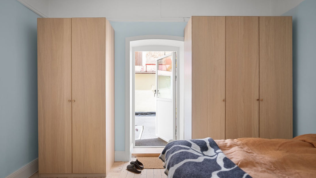 Large flat timber wardrobe doors beside a bed in a bright bedroom