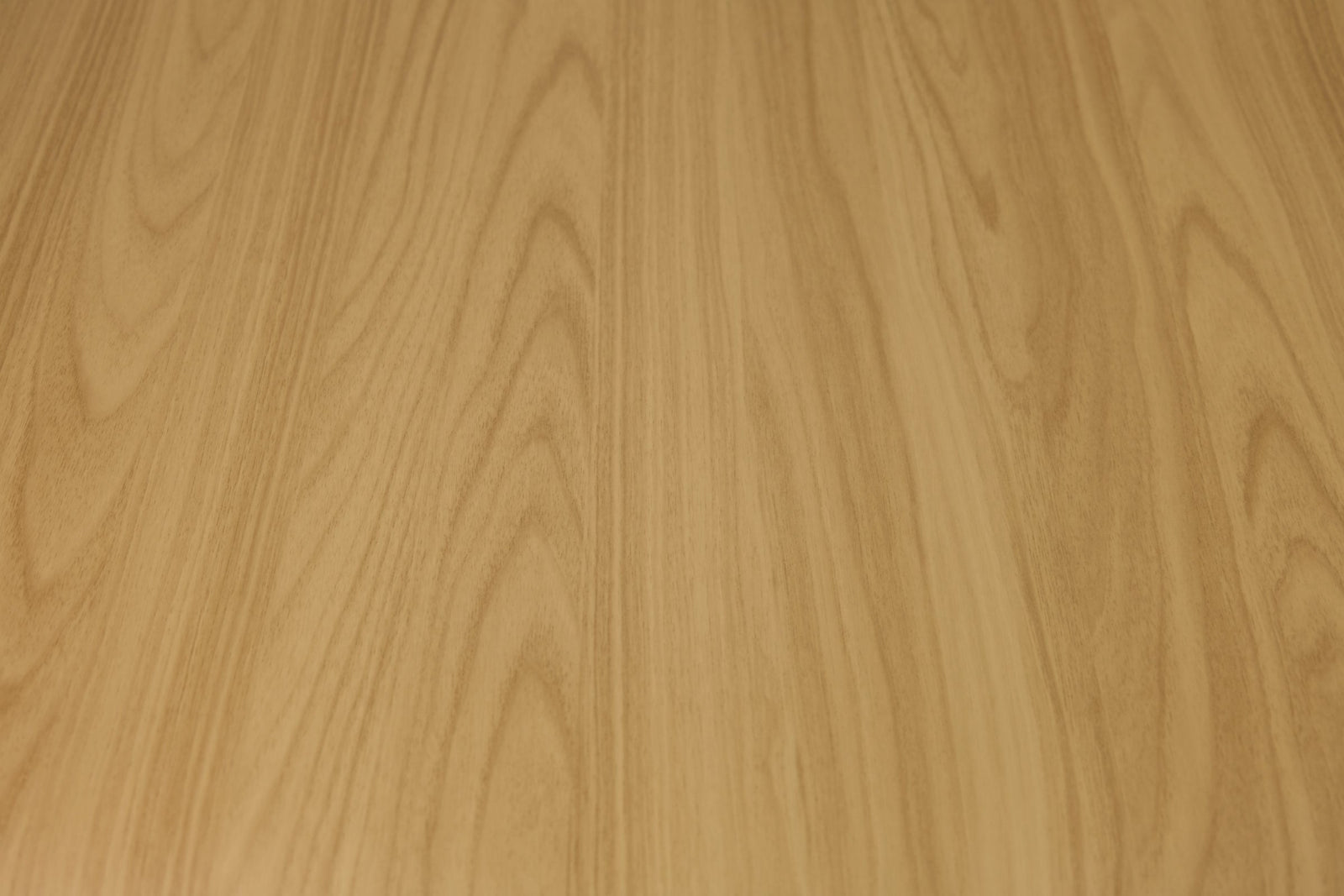 Soft blonde oak peel and stick wrap sample held against a warm wall