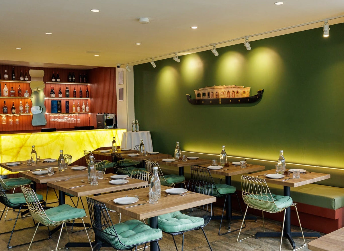 Restaurant tables wrapped in Saddle Teak wood grain, set for service against a green wall
