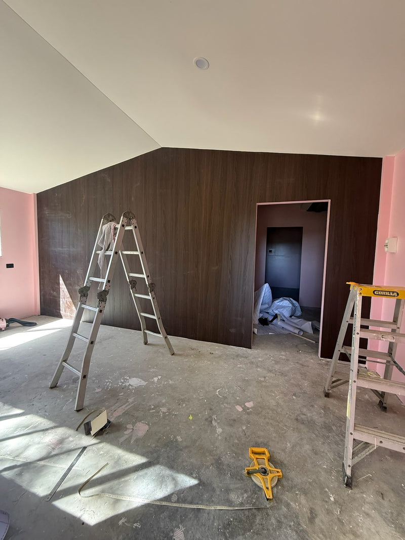 Feature wall wrapped in dark wood grain vinyl in a renovated room with pink side walls