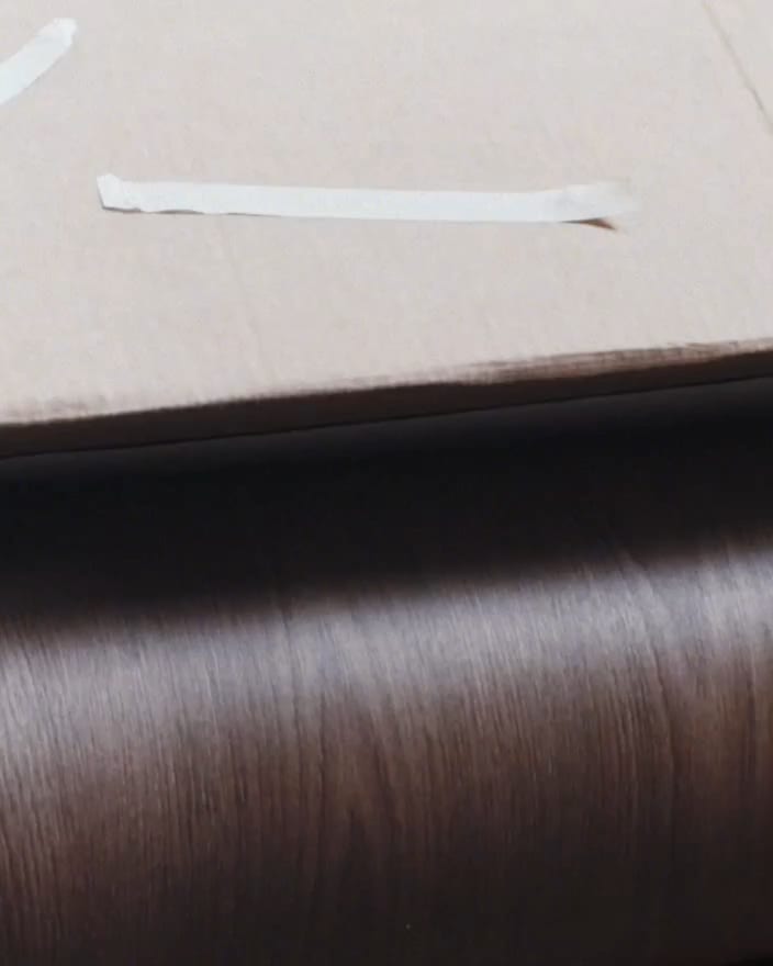A roll of Maison Walnut wood grain wrap on its white release paper, ready to go up at The Feel Good Hood